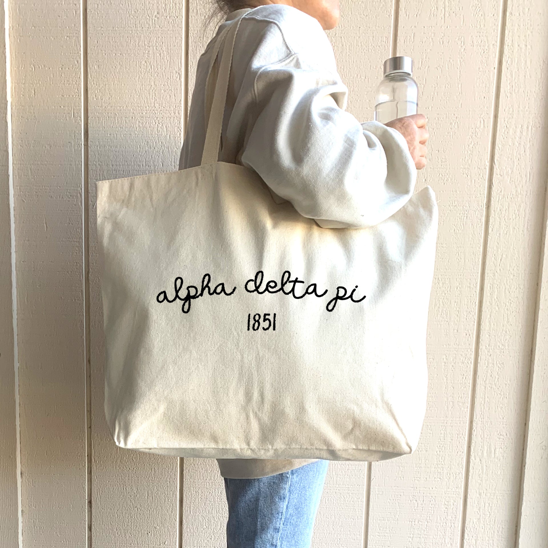 Alpha Delta Pi – A smiling college student walks across campus carrying an Alpha Delta Pi canvas tote, perfect for books and daily essentials.