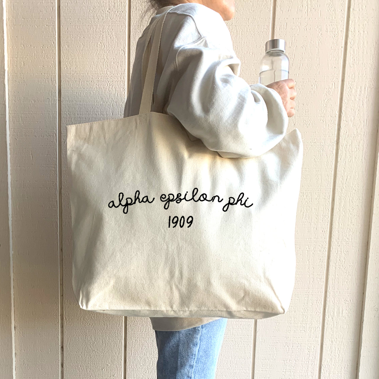 A fashionable college student sports an Alpha Epsilon Phi tote, making a statement while heading to class, the gym, or Greek life events.