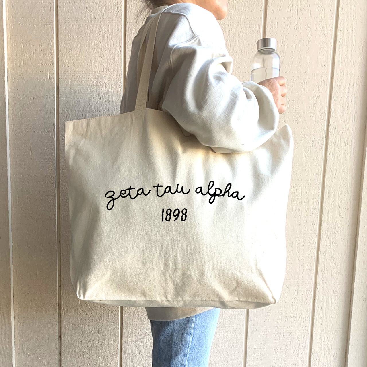 A student confidently carries her Zeta Tau Alpha tote, a fashionable way to showcase her sorority sisterhood.