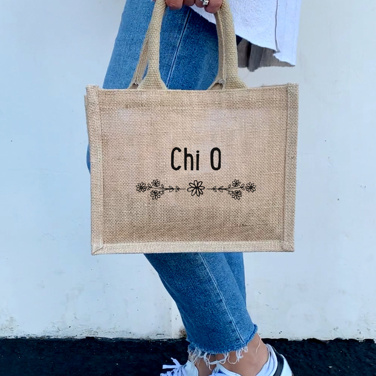 A model carrying the floral burlap tote with Chi Omega design, highlighting the perfect blend of functionality and sorority pride.