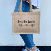 A model sporting the Delta Phi Epsilon floral burlap tote, the ideal way to represent your sorority with style and flair.