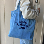 Model holding a Alpha Epsilon Phi sorority denim blue tote bag, stylish and spacious for everyday use