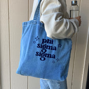 Model holding a Sigma Sigma Sigma sorority denim blue tote bag, stylish and spacious for everyday use