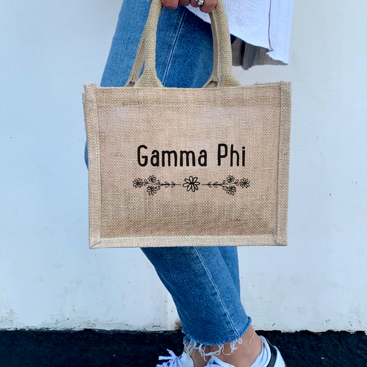 A model with the Gamma Phi Beta floral burlap tote, combining sorority spirit with everyday function and style.