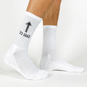 Arrow pointing to the grad with '2025' printed on socks—fun graduation gift for the Class of 2025.