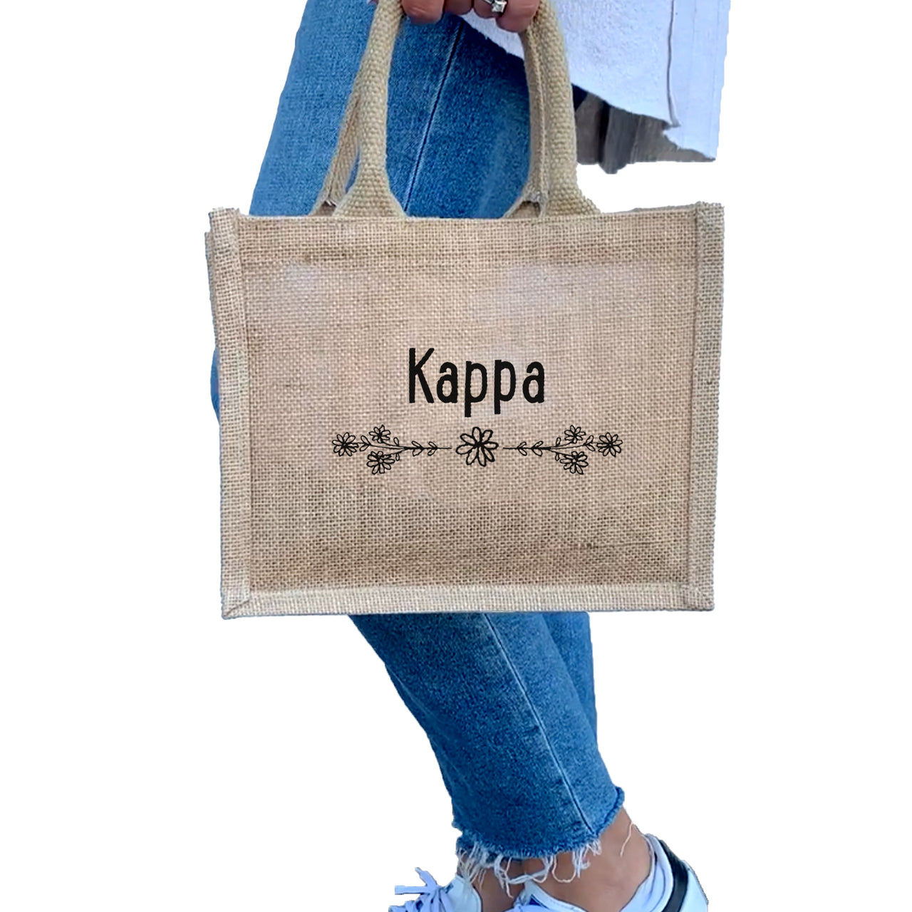 A model carrying the Kappa Kappa Gamma floral burlap tote, the ideal way to showcase your Greek pride every day.