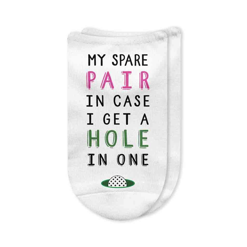 A pair of white no-show golf socks for women featuring the phrase "My Spare Pair in Case I Get a Hole in One" printed on top, a fun and playful gift for female golfers.