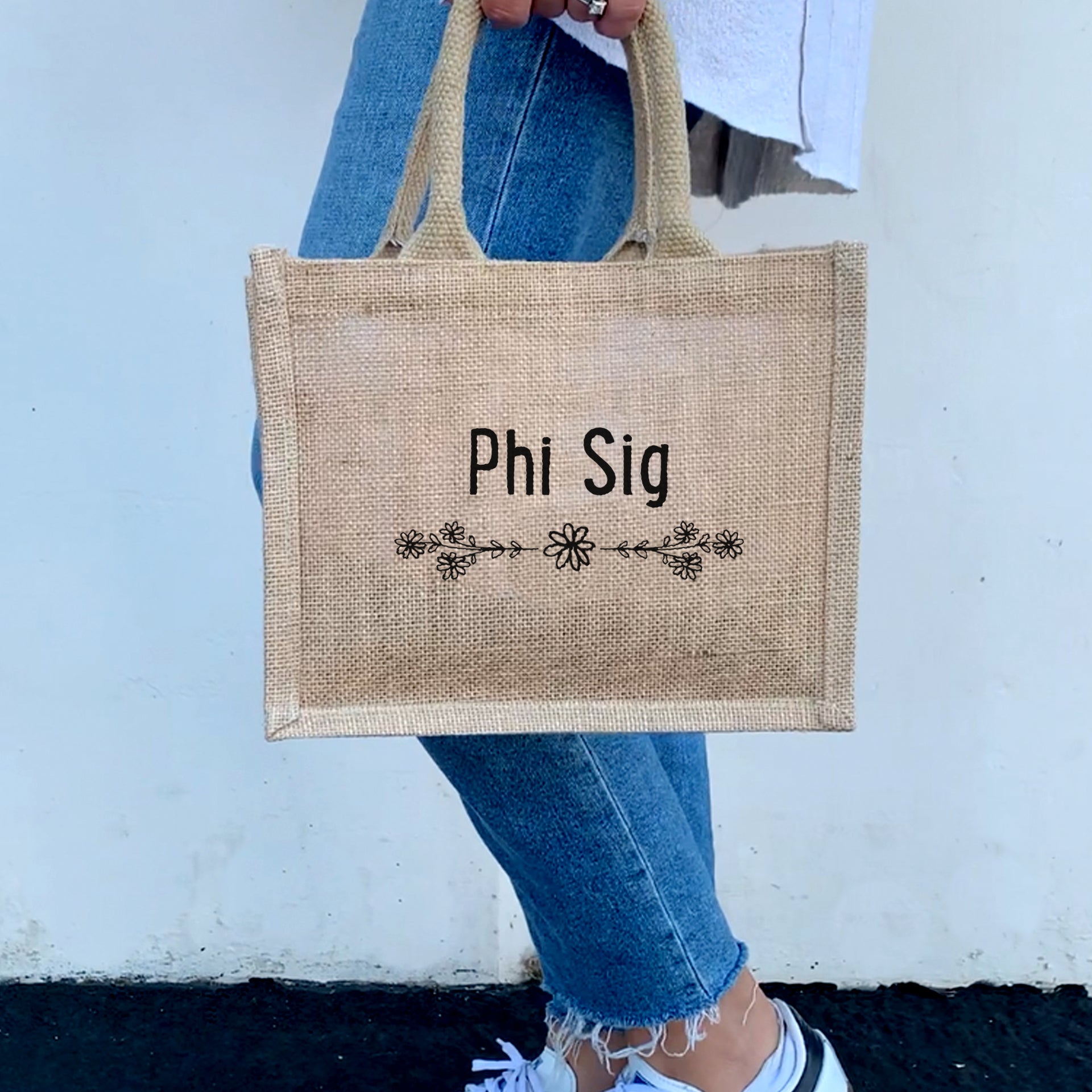 A model with the Phi Sigma Sigma floral burlap tote, perfect for carrying all your sorority essentials with a touch of style.