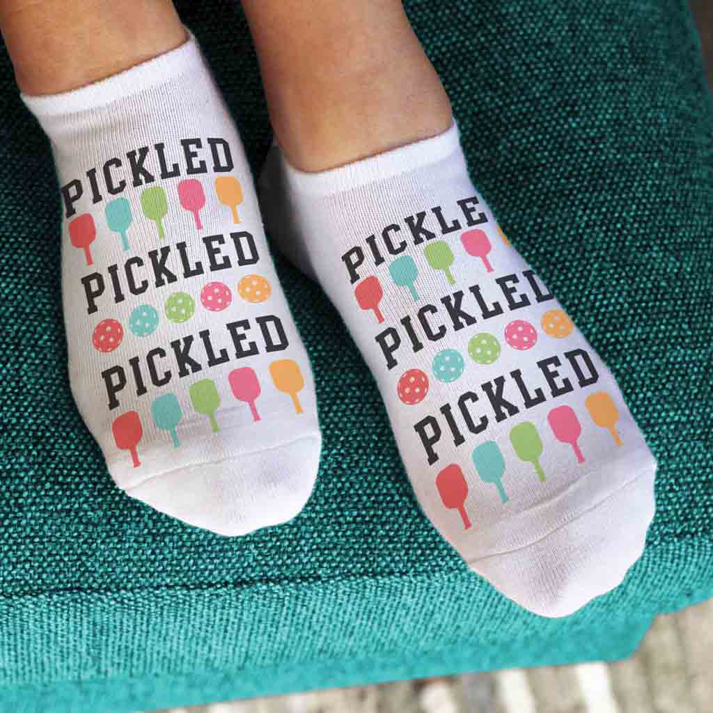 Bring on your pickleball game with our Pickled pickleball socks, featuring a cute design of colorful pickleball paddles repeating with the word Pickled.  Designed for both comfort and style, these socks add a touch of fun to your on-court look. Step onto the court with confidence and show off your pickleball passion with every step you take.